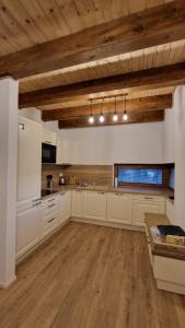 a large kitchen with white cabinets and wooden ceilings at Mytho 1 in Mýto pod Ďumbierom