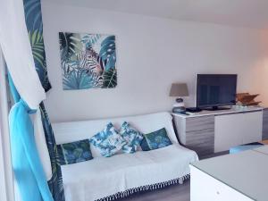 a living room with a white couch and a tv at Studio entre ciel et mer sans coupure d'eau in Le Gosier