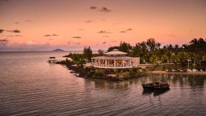 LUX* Grand Gaube Resort & Villas في غراند غايوب: منتجع في جزيرة في ماء وقت الغروب