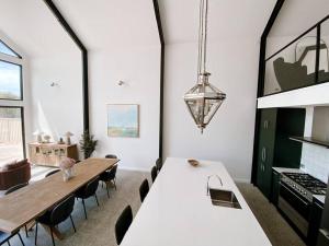 Le Soleil new villa, golf & heated pool في دانسبورو: مطبخ وغرفة طعام مع طاولة بيضاء كبيرة وكراسي