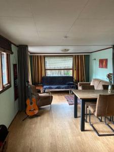 uma sala de estar com um sofá, uma mesa e uma guitarra em Welcome, relax and enjoy your stay em Putten