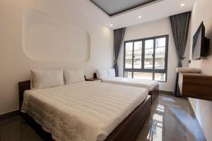 a bedroom with two beds and a window at Cassie Boutique Hotel in Vung Tau