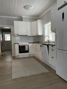 cocina con electrodomésticos blancos y suelo de madera en Helsingegården en Järvsö