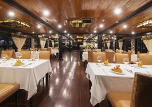 Arcady Boutique Cruise في ها لونغ: غرفة طعام مع طاولات وكراسي بيضاء