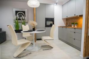 kuchnia z białym stołem i białymi krzesłami w obiekcie Nowoczesny apartament Ludova w mieście Biskupiec