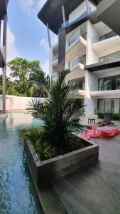 a building with a palm tree next to a swimming pool at CYAN Resort Kamala Beach Apartments Condominiums in Kamala Beach