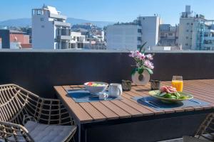 a wooden table with two plates of food on a balcony at Luxury Penthouse with Acropolis View and Jacuzzi in Athens