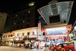 uma rua da cidade movimentada à noite com pessoas e edifícios em D Loft Hotel em Kuala Lumpur