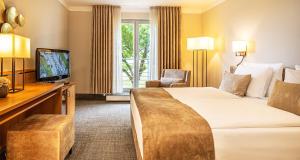 una camera d'albergo con un letto e una televisione di Victor's Residenz-Hotel Teistungenburg a Teistungen