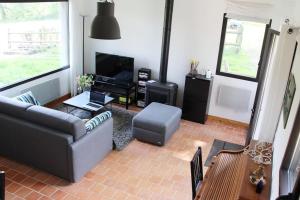 a living room with a couch and a television at Maisonnette au calme, 15 kms Honfleur/Deauville in Les Authieux-sur-Calonne