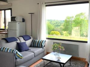 - un salon avec un canapé, une table et une fenêtre dans l'établissement Maisonnette au calme, 15 kms Honfleur/Deauville, à Les Authieux-sur-Calonne