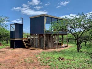 a house with a staircase in the middle of a field at Mudhouse Zululand in Hluhluwe