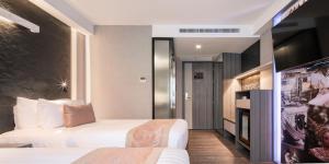 a hotel room with two beds and a tv at Aspira Gems Center Silom in Bangkok