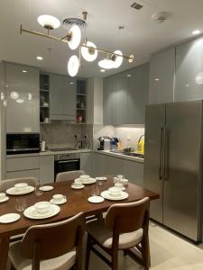 a kitchen with a wooden table with chairs and a refrigerator at Two Bedroom Apartment Address Residence - Fujairah in Fujairah