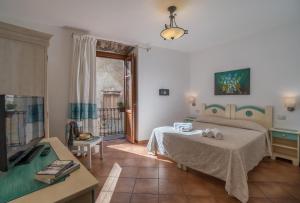 a room with a bed and a table and a television at Bosa Queen House in Bosa