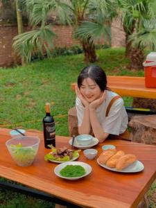 a woman sitting at a picnic table with food on it at The Bright House Villa - Venuestay in Hanoi