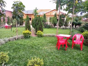 three red chairs and a table in a yard at Nuc-Fey Lodging in Kigali