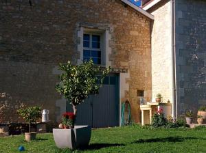 ein Haus mit einer blauen Tür und einem Baum im Gras in der Unterkunft La Ferme des Augustines in Belluire