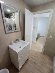 a bathroom with a white sink and a mirror at Piso Avenida junto a la Playa in Cádiz