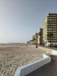 a sandy beach with buildings and people on it at Piso Avenida junto a la Playa in Cádiz