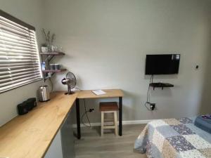 escritorio en una habitación con cama y escritorio con TV en Platform 162 en Ciudad del Cabo