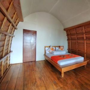 a bedroom with two beds and a wooden floor at Air Belanda Resort "Near Ora Beach" in Kaloa