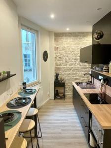 una cocina con 2 lavabos y una pared de piedra en APPARTEMENT 1 CHAMBRE AVEC ENTREE INDIVIDUEL en Chalon-sur-Saône