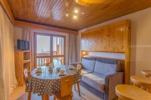 uma sala de estar com uma mesa e um sofá em Les Dryades - Appartement lumineux avec grand balcon et vue sur la montagne em Les Allues