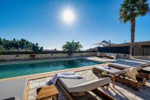 einen Pool mit Stühlen, einem Tisch und einer Palme in der Unterkunft Palmrise Luxury Villas by Travel Pro Services - Nea Skioni Halkidiki in Nea Skioni