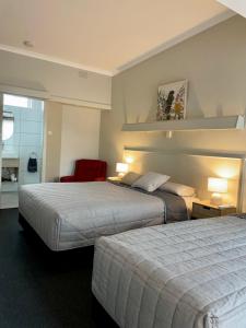 a hotel room with two beds and a red chair at Tarra Motel in Yarram