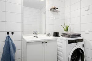 biała łazienka z pralką i umywalką w obiekcie Moderne leilighet - nært flyplass - lader for elbil w mieście Råholt