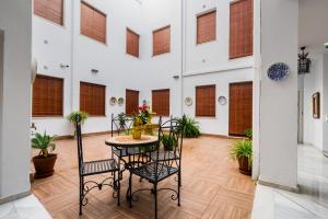 a room with a table and chairs and windows at Apartamentos Cruz de San Andrés in Seville