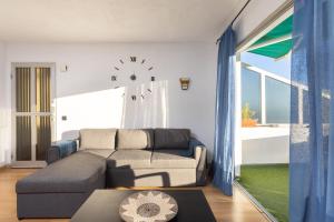 a living room with a couch and a clock on the wall at Home2Book Lovely Ocean Views Apt Tabaiba in Tabaiba