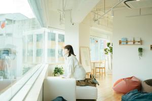 a woman sitting on a couch in a living room at Norden Ruder Hostel Taichung in Taichung