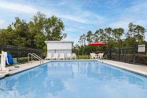 uma piscina com cadeiras e um guarda-sol em Days Inn by Wyndham Pensacola I-10 em Pensacola