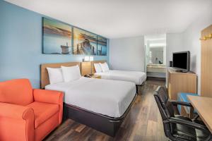 a hotel room with two beds and a chair at Days Inn by Wyndham Pensacola I-10 in Pensacola