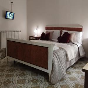 LenolaにあるPetalo Rosso b&bの大型ベッド1台、壁にテレビが備わるベッドルーム1室を利用できます。
