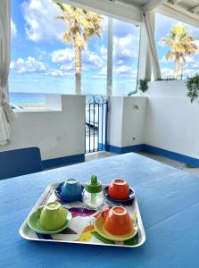 - un plateau avec des assiettes et des tasses de différentes couleurs sur une table dans l'établissement Casa della Ghiacciaia, à Capo dʼOrlando