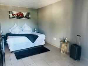 a bedroom with a bed and a suitcase in it at Tsamatiku Villa Guesthouse in Hazyview
