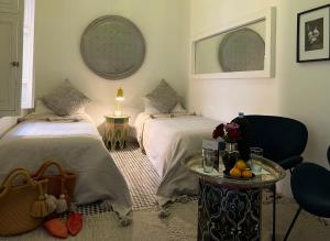 una camera da letto con due letti e un tavolo con una lampada di Riad Albatoul a Marrakech Altre 37 foto