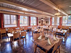 Un restaurante con mesas y sillas de madera y ventanas. en Hotel Pinzgauerhof by Alpeffect Hotels, en Zell am See