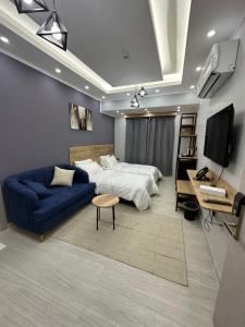 Al AmaratにあるBlue Rose Hotelのベッドルーム(ベッド1台、青いソファ付)
