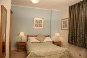 1 dormitorio con 1 cama, 2 lámparas y ventana en Tamasha Hotel, en Bromley