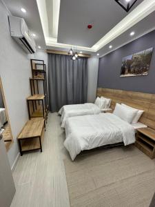 um quarto com duas camas e uma televisão na parede em Blue Rose Hotel em Al Amarat