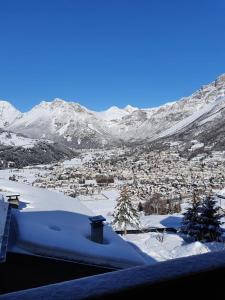 una ciudad cubierta de nieve con montañas en el fondo en Casa Grafa Bormio en Valdisotto