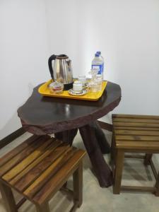 a table with a tea kettle on it next to two chairs at Dew Safari Cottage in Udawalawe