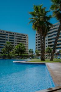 a swimming pool with palm trees and buildings at Panorama Mar Apartment in Punta Prima