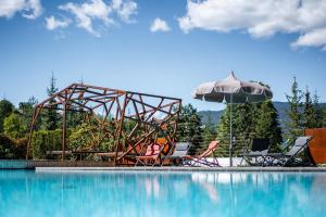 a pool with chairs and an umbrella next to a pool at Camping Seiser Alm in Völs am Schlern