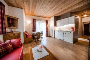 a living room with a red couch and a kitchen at Camping Seiser Alm in Völs am Schlern