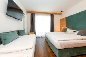 una camera d'albergo con due letti e un divano di Bepy Hotel Garni a Giustino